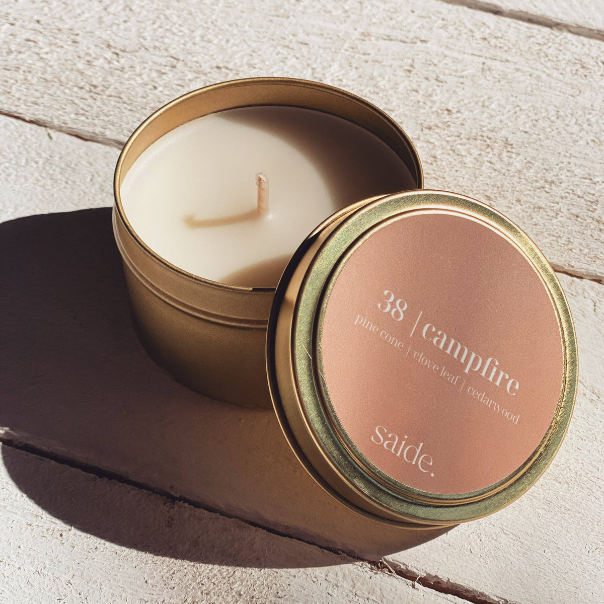Scented candle in a tin with '38 Campfire' label on a wooden surface