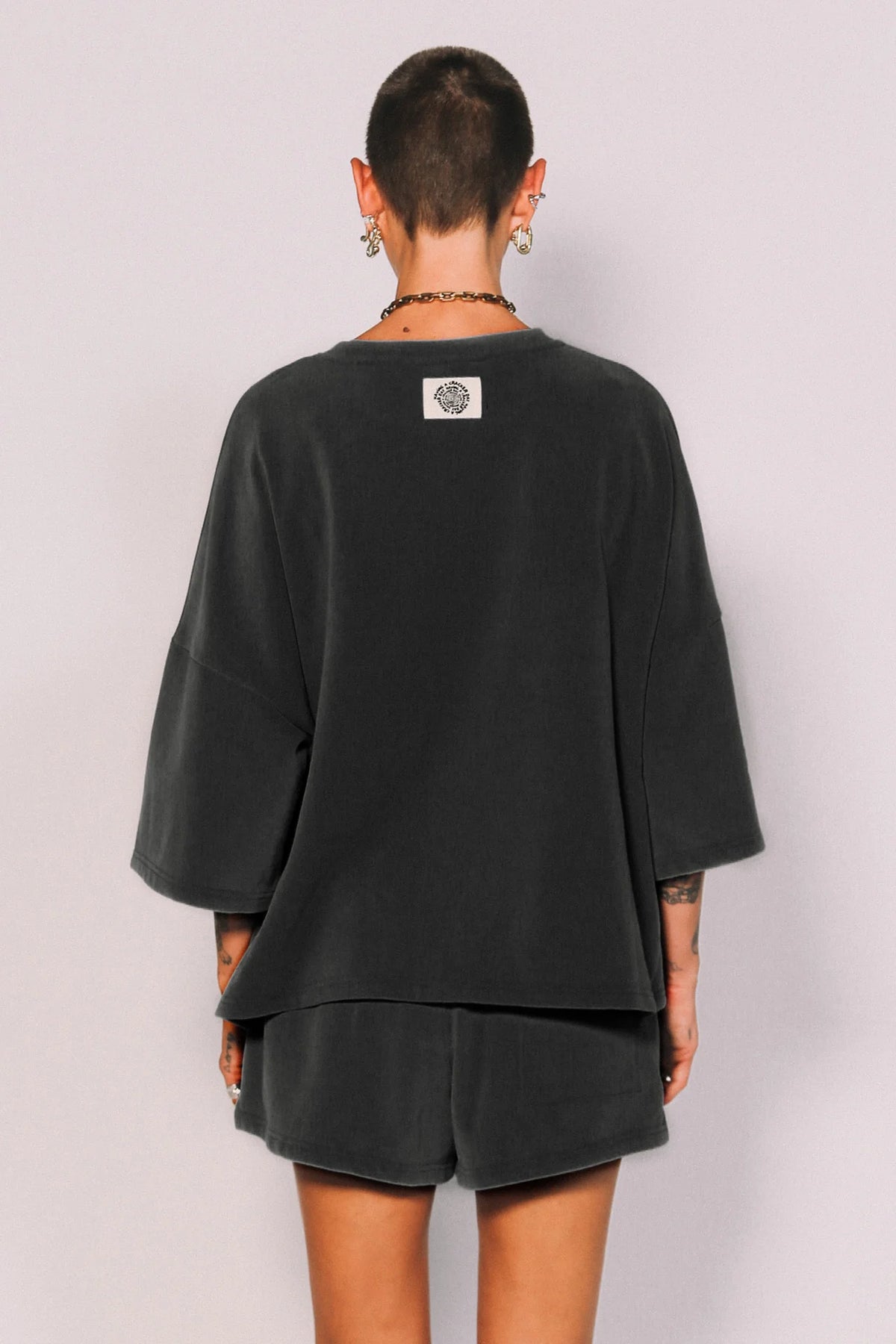 Person wearing a black oversized top and shorts set on a plain background