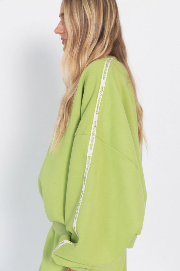 Woman wearing a green hoodie with white text on the sleeves against a white background