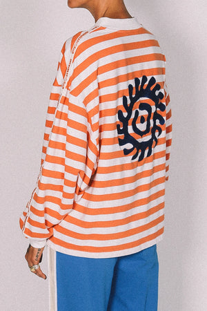 Person wearing an orange and white striped shirt with a black graphic design on a plain background