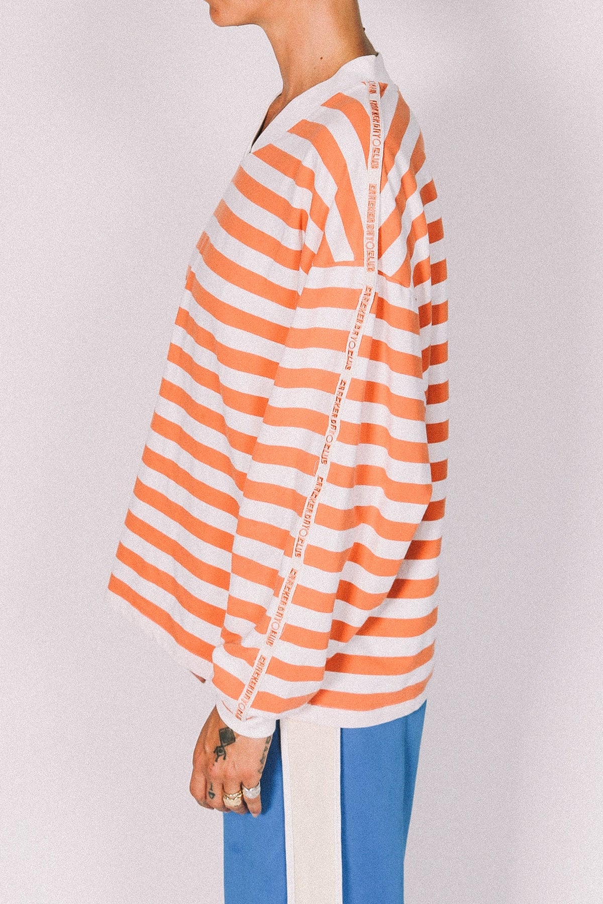 Person wearing an orange and white striped shirt with a plain background