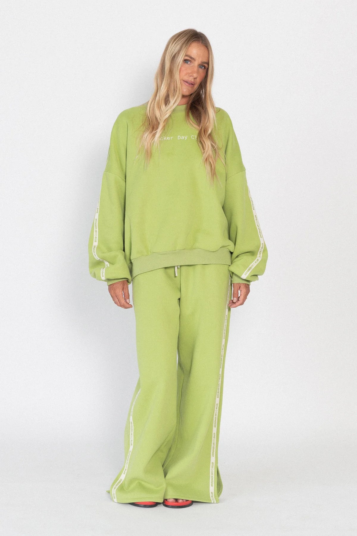 Person wearing a green tracksuit with white stripes on a white background