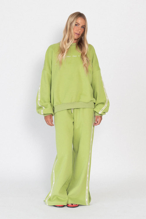Person wearing a green tracksuit with white stripes on a white background