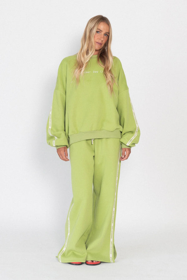 Person wearing a green tracksuit with white stripes on a white background