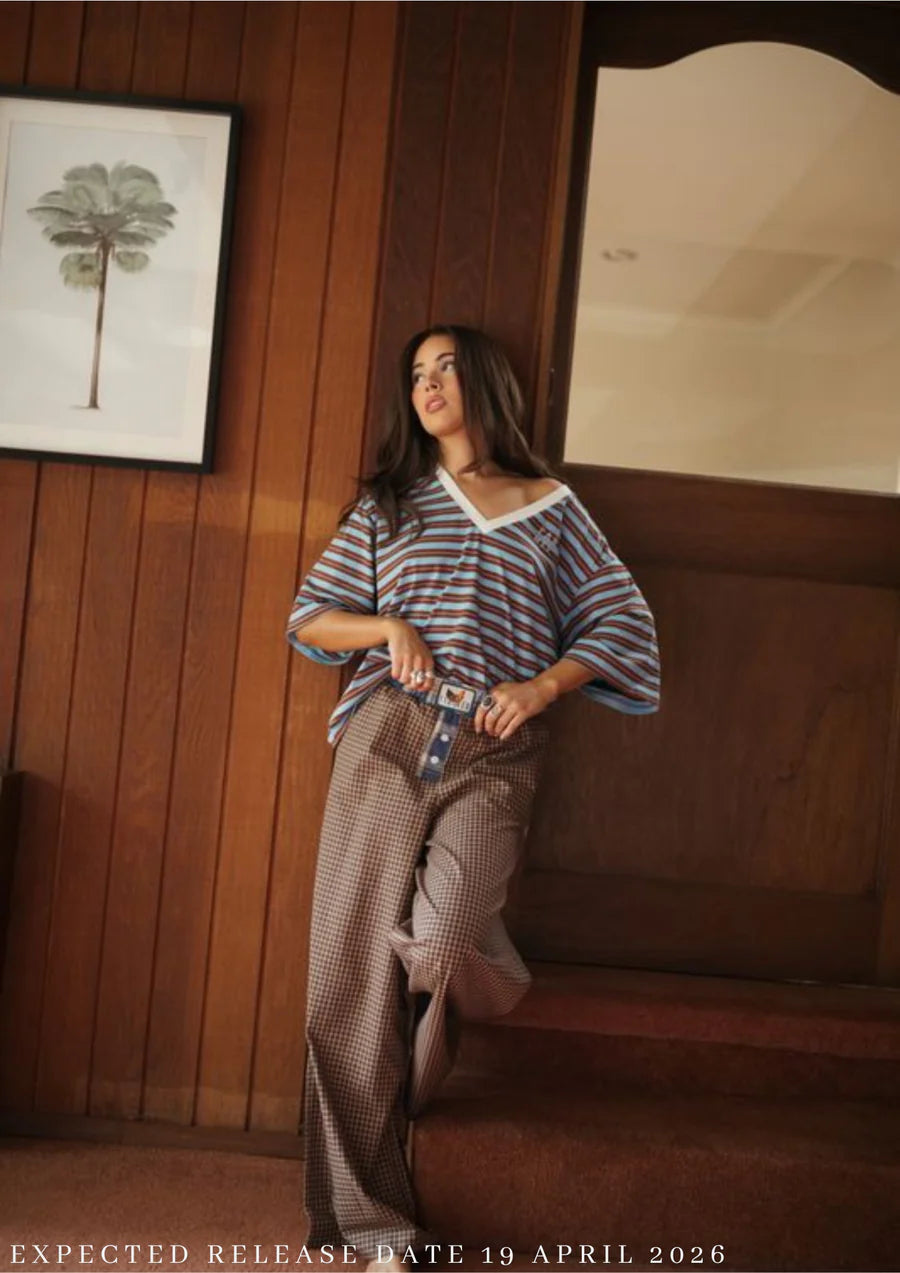 Woman wearing FAR MER by Whitney Stripe Tee and Boyfriend Plaid Pants from ALL MY EXES range - standing against timber wall in house