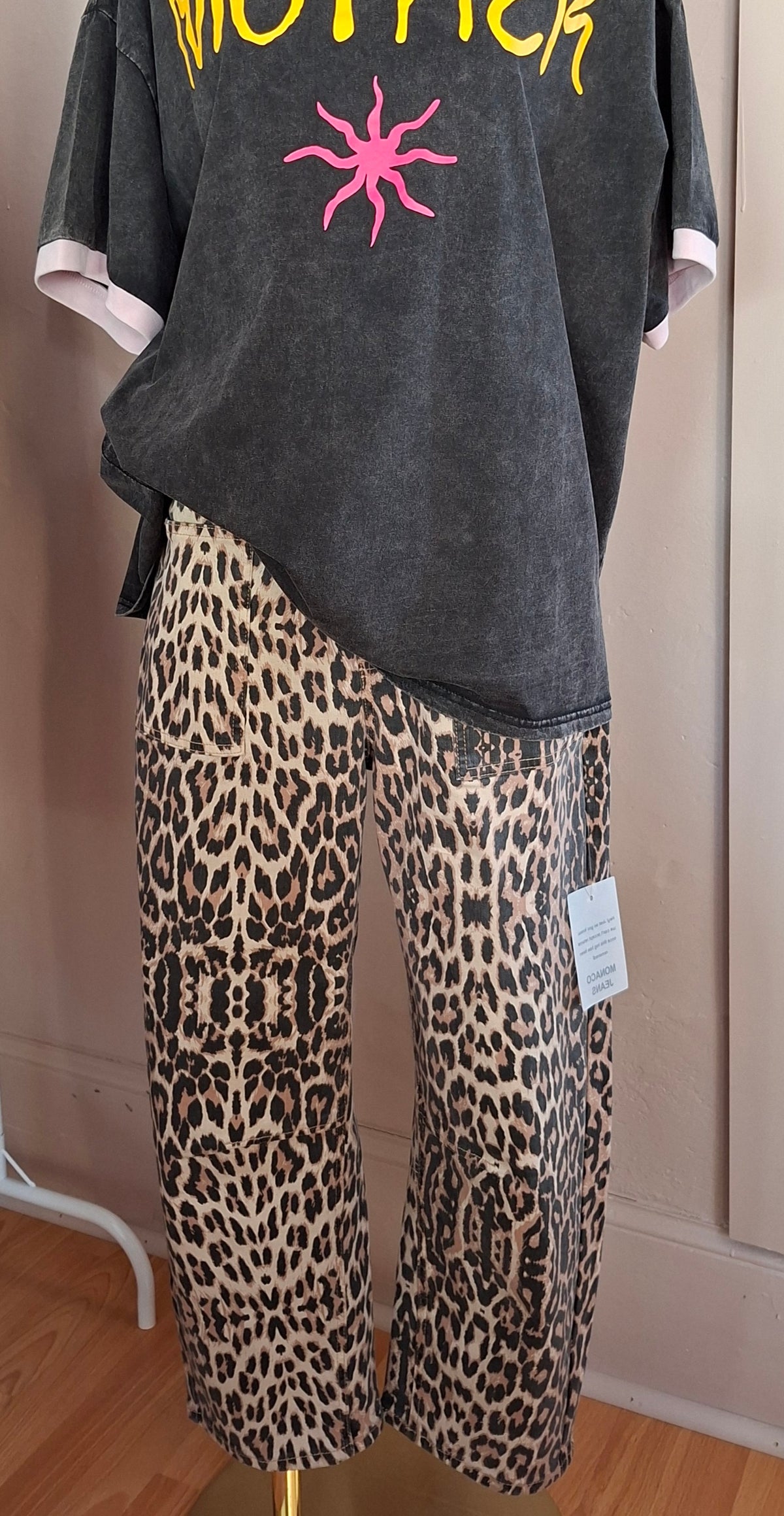 Gray oversized t-shirt with pink star design and leopard print pants on a mannequin against a neutral wall.
