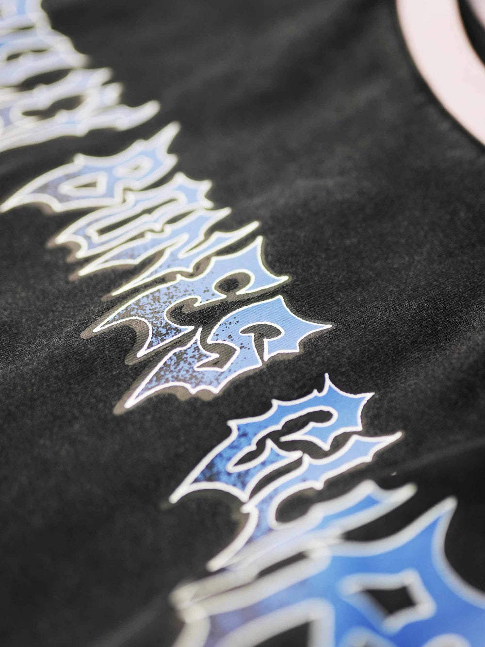 Close-up of a black shirt with blue and white graphics and text.