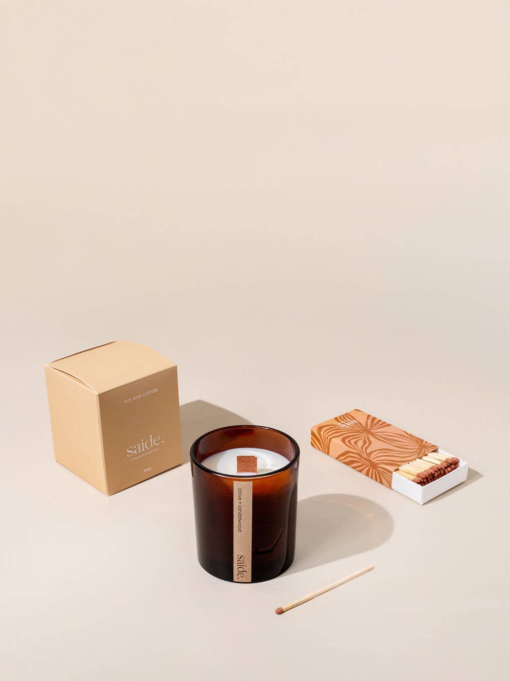 A candle with packaging and matches on a beige background