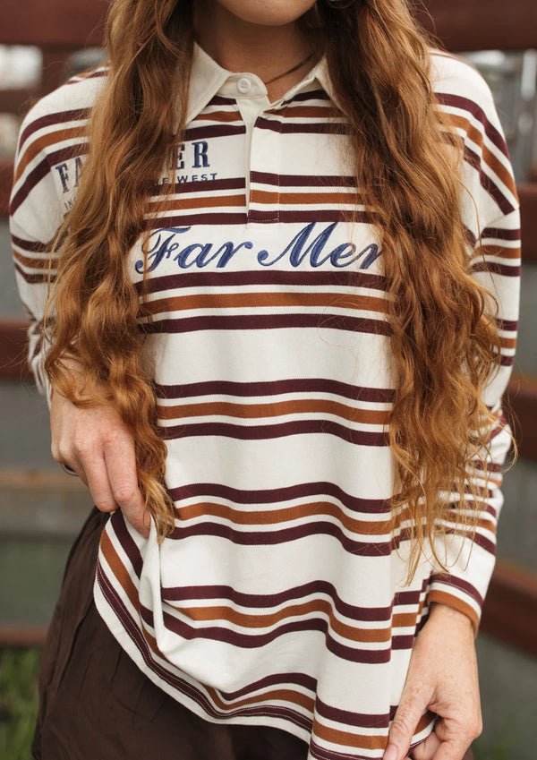 A woman wearing a long-sleeve collared polo shirt with horizontal brown and rust stripes on an off-white background, featuring 'Far Mer' in navy script across the chest.