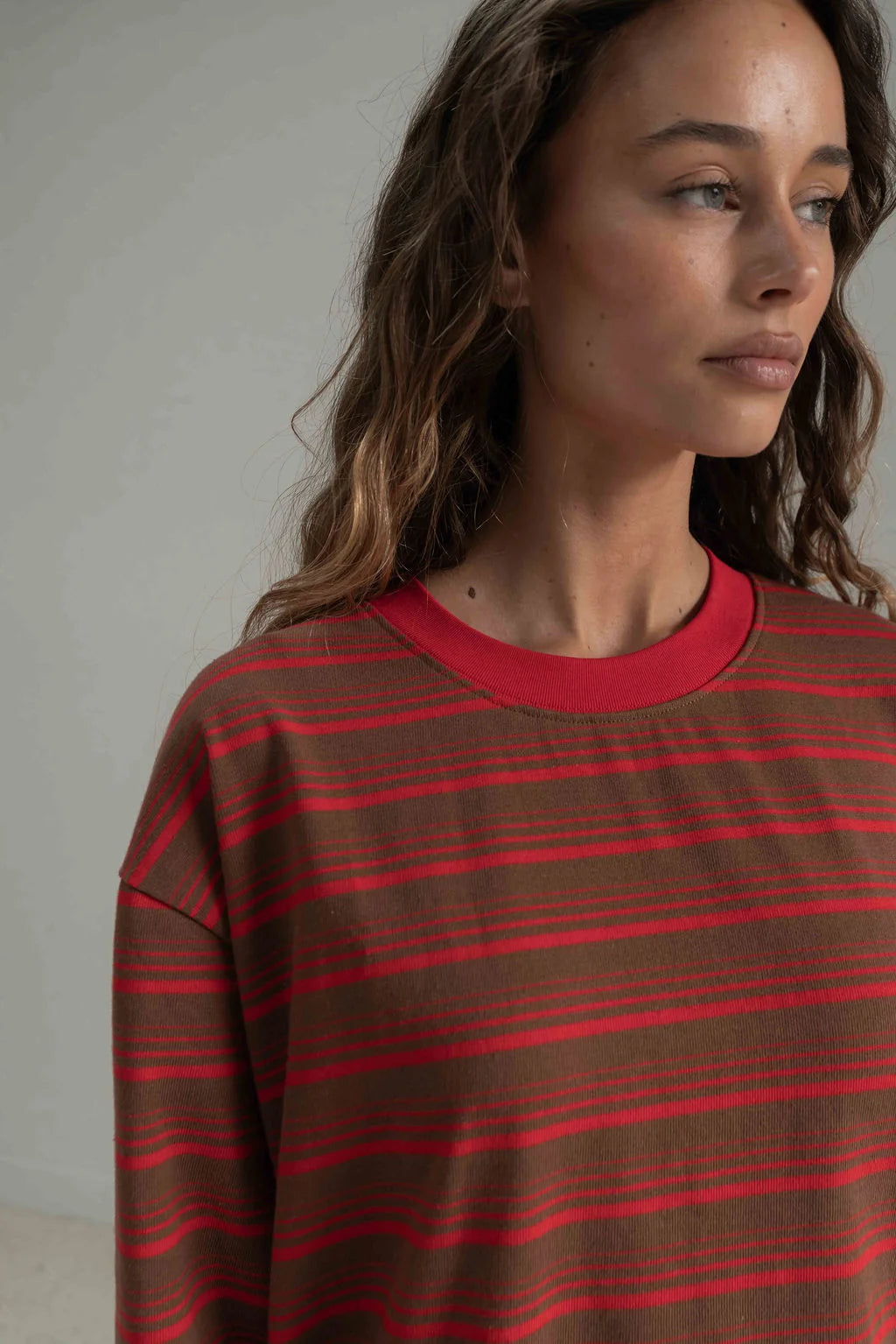 close up of a woman with her hair down wearing a brown and red long sleeve tee