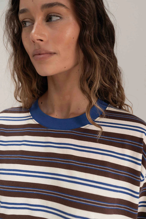 Close up of woman with hair down wearing striped blue brown and oat long sleeve tee 