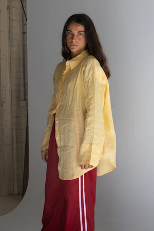 girl standing near wall wearing crimson linen pants and yellow linen shirt