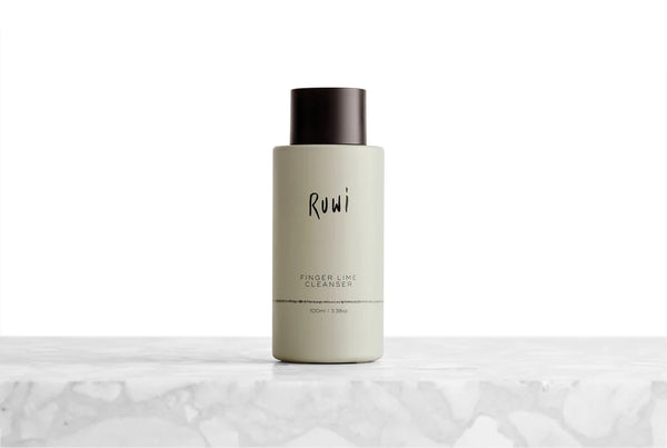 A bottle of Rumi Finger Lime Cleanser standing upright on a light marble surface against a white background.