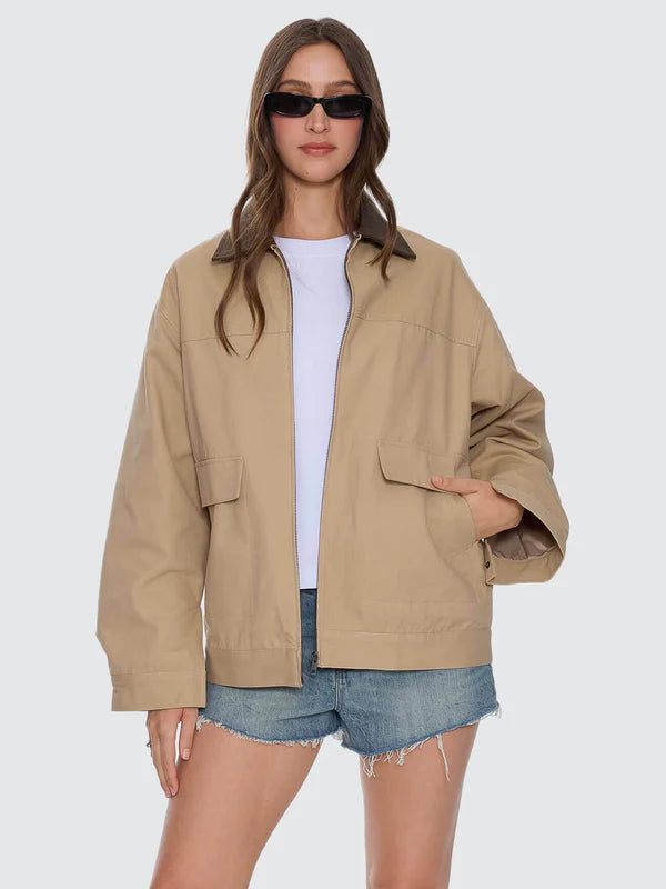 Woman wearing a beige jacket, white shirt, and denim shorts on a white background